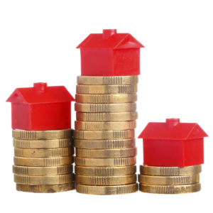 Red small house on top of stacks of coins isolated on white background.