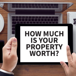 HOW MUCH IS YOUR PROPERTY WORTH? , on the tablet pc screen held by businessman hands - online, top view